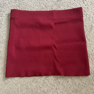 Vinröd ribbad minikjol - Säljer en vinröd ribbad minikjol med tight passform. Kjolen är enkel och stilren utan detaljer, perfekt att matcha med en crop top eller hoodie. Materialet är stretchigt och följsamt, vilket gör den superbekväm att bära. Perfekt som en topp också!