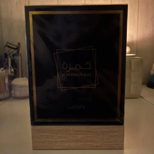 Lattafa Khamrah parfym 100ml - Säljer en helt ny oöppnad elegant parfym från Lattafa, Khamrah 100ml. Förpackningen är stilren i svart med gyllene detaljer och arabiska inskriptioner. 