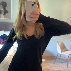 Svart v-ringad tröja från Lindex - En svart, enkel och stilren v-ringad tröja från Lindex i storlek M. Tröjan har lång ärm och en normal passform, perfekt att matcha med jeans eller kjol. Materialet är mjukt och känns skönt mot huden.