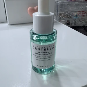 Centella Tea-Trica Relief  - Centella Tea-Trica Relief Ampoule från SKIN1004 är ett ansiktsserum i en genomskinlig glasflaska med pipett. Innehållet är ljusgrönt och består av centella-extrakt från Madagaskar. Flaskan rymmer 30 ml och har en vit pipettkork för enkel applicering.