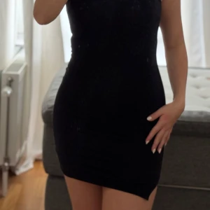 Svart tight klänning PrettyLittleThing - Svart, tight, simpel och ärmlös kortklänning från PrettyLittleThing. Klänningen har hög halsringning och är gjord i mjuk bomull. Enkel och stilren modell som sitter figurnära! Perfekt ”little black dress” för en utekväll eller bara för att🖤