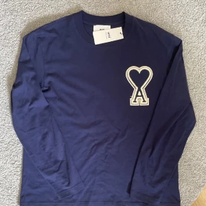  Ami Paris sweatshirt  - Säljer sprillans ny en mörkblå långärmad tröja från Ami Alexandre Mattiussi med det ikoniska hjärta-A broderiet på bröstet. Tröjan har rund halsringning och är tillverkad i mjuk bomull. Perfekt för en stilren och avslappnad look. Hör av er vid frågor! Pris kan diskuteras!