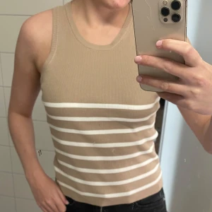 Linne från Pernilla Wahlgren - Snygg ribbad linnetopp i beige med vita ränder. Ärmlös modell med rund halsringning. Sprillans ny! Aldrig använd då jag köpte i fel storlek..
