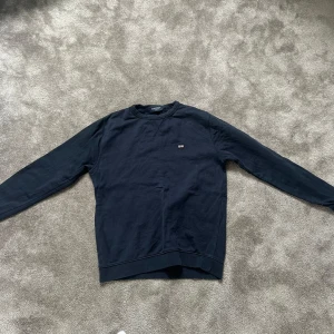 Mörkblå sweatshirt från Lexington - En stilren mörkblå sweatshirt från Lexington med liten logga på bröstet. Tröjan har rund halsringning och långa ärmar. Perfekt för en avslappnad och snygg look.