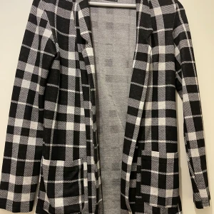 Kofta  - Snygg svartvit rutig kavaj från FB Sister i storlek XS. Jackan har klassisk kavajkrage, två fickor framtill och är helfodrad. Perfekt för dig som gillar en stilren och trendig look med lite edge.