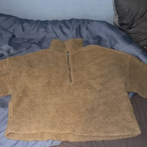 Beige fleece tröja med dragkedja - Mysig beige fleece tröja med halv dragkedja och hög krage. Perfekt för kyliga dagar när du vill hålla dig varm och bekväm. Tröjan har en avslappnad passform och är lätt att matcha med andra plagg.