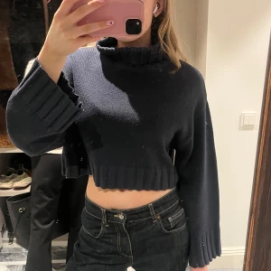 Mörkblå croppad stickad tröja - Säljer en mörkblå croppad stickad tröja med långa ärmar och ribbade detaljer vid ärmslut och nederkant. 