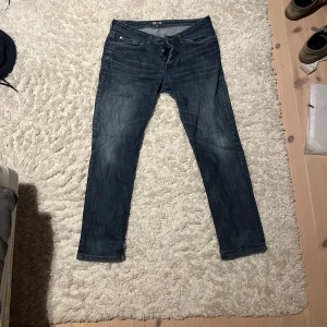 Blå jeans från Denim - Snygga blå jeans från Denim med en klassisk femficksdesign och knappar i gylfen. Jeansen har en straight passform och är perfekta för en avslappnad stil. De har en lätt tvättad look som ger en cool vibe.