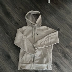 Beige hoodie från Peak Performance - Säljer en snygg beige hoodie från Peak Performance i utmärkt skick, använd ett fåtal gånger eftersom tröjan var för liten när jag fick den:)