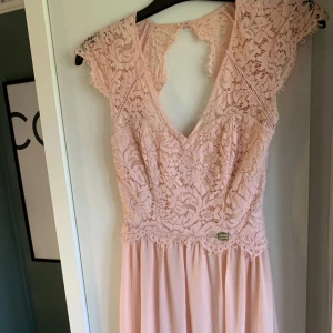 Ljusrosa spetsklänning - Elegant ljusrosa klänning med spetsdetaljer och v-ringning. Klänningen har en vacker spetsöverdel och en flödande kjol. Perfekt för sommarens festligheter eller supé/bal 🤩 skriv om ni har några frågor ❤️