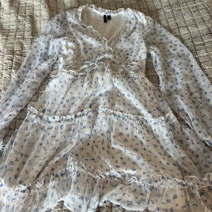Vit blommig klänning från Vero Moda!🌸 - Säljer en söt vit klänning med blå blommor från Vero Moda!. Klänningen har långa ärmar och volangdetaljer vid halsen och kjolen. Perfekt för vår och sommar! 🌸Det är storlek s i klänningen, vid fler frågor eller bilder skriv till mig! 