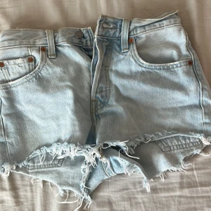 Ljusa jeansshorts från Levi's - Säljer ett par ljusa jeansshorts från Levi's med fransiga kanter. Shortsen har en klassisk femficksdesign och knappgylf. 💖