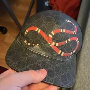 Gucci keps - Snygg svart keps från Gucci med ett iögonfallande ormmönster lite sliten
