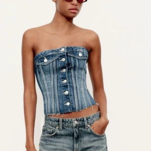 Jeans tubtopp med knappar - Trendig jeans tubtopp med knappar framtill och dekorativa fickor. Perfekt för en avslappnad och stilren look.PRIS GÅR ATT DISKUTERA 