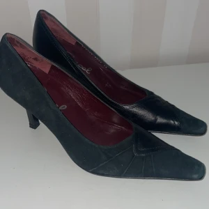 Svarta pumps från Gracel - Eleganta svarta pumps från Gracel med spetsig tå och klack(7 cm) Skorna har en stilren design med en kombination av skinn och mocka. Perfekta för en chic look.