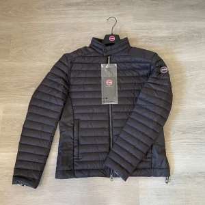 Colmar jacka strl 52/L - Marinblå Colmarjacka i lättviktsdun. Helt ny med tags och galge. En perfekt jacka för vår/höst eller kyligare sommarkvällar. Liten i storleken.  Nypris ca 3500kr. Jag säljer även en likadan i storlek 50/M.