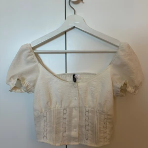 Vit blus med spetsdetaljer - Charmig vit blus med korta puffärmar och spetsdetaljer framtill. Blusen har knappar längs framsidan och en söt, feminin stil. Storlek xs💗