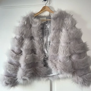 Fluffig pälsjacka - Grå fuskpäls jacka från Vera&Lucy. Aldrig använts. Storlek XS, kan även passa S och M. Säljer en lyxig grå pälsjacka med fluffig textur och glansigt foder. Jackan har en öppen design utan knäppning 