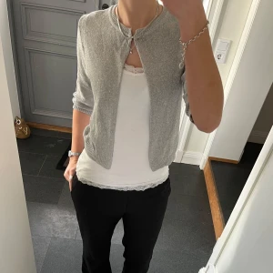 Grå stickad kofta  - Grå/glittrig trekvartsärmad stickad kofta från V Milano i fint skick. Kan inte hitta storlek men skulle säga S/M. Använd gärna köp nu!