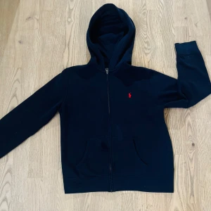 Mörkblå hoodie från Ralph Lauren - Jag säljer min marinblåa ralph lauren zip hoodie nu då den inte kommer till användning. Den är i super bra skick nästan aldrig använt💕den passar både tjejer och killar och den är i storlek 14-16 men passar mig som är 160cm , den är lite stor för mig så passar upp till 165 cm skulle jag säga🥰nypris är 1100kr mitt pris är 750kr!❤️