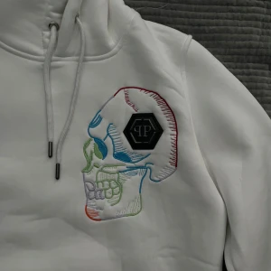 Vit hoodie från Philipp Plein  - Säljer en vit hoodie från Philipp Plein med stor broderad döskalle i flera färger på bröstet och klassisk PP-logga. Är storlek M men sitter passar S eftersom jag har S.