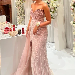 Ljusrosa glittrig balklänning med slits - Säljer en ljusrosa långklänning med glittriga detaljer och snygg slits framtill. Klänningen har axelbandslös sweetheart-ringning, markerad midja och ett långt släp i tyll. Perfekt för bal eller fest, riktigt drömmig och elegant look.