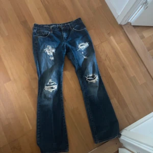 Blå slitna bootcut jeans med detaljer - Midjan är 40cm tvärsöver & innerbenslängden är 77cm. Köpte jeansen för 700kr❤️