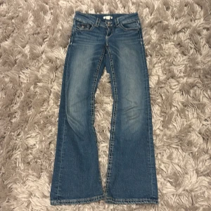 Blå bootcut jeans Gina Tricot 158 - Snygga blå jeans från Gina Tricot i klassisk bootcut-modell. Jeansen har normal midja, fem fickor och coola slitningar framtill. Materialet är mjukt denim i bomull och passformen är relaxed med utsvängda ben. Perfekta för en chill och trendig look.