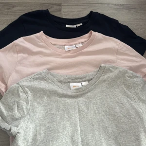 3-pack basic t-shirts från Gina Tricot - Säljer ett 3-pack basic t-shirts från Gina Tricot i storlek S. En gråmelerad, en ljusrosa och en svart t-shirt, alla i mjuk bomull med rund hals och korta ärmar. Perfekta att matcha med jeans eller shorts för en enkel och clean look.