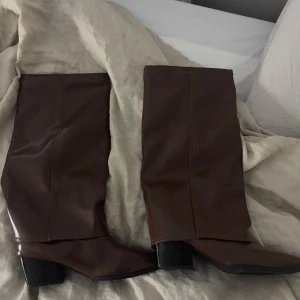 Bruna stövlar med klack  - Aldrig använda snygga bruna stövlar i skinnimitation med spetsig tå och markerad klack. Stövlarna är även glansiga