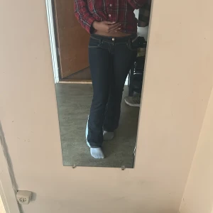 Mörkblå bootcut jeans med kontrastsömmar - Säljer ett par mörkblå bootcut jeans med snygga kontrastsömmar och klassiska fickor både fram och bak. Jeansen har låg midja och är tillverkade i ett stretchigt jeansmaterial som sitter tajt upptill och släpper ut vid bensluten.dom är xxs/xs