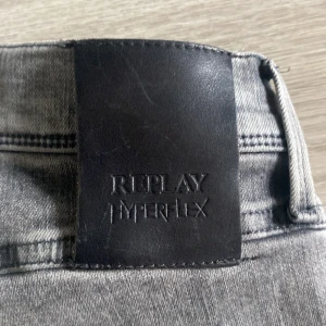 Replay Hyperflex Anbass grå jeans - Snygga Replay Hyperflex Anbass jeans i grå tvätt med klassisk femficksdesign. Jeansen har en slim passform och är tillverkade i stretchigt jeansmaterial som ger extra komfort. Perfekta för dig som gillar en modern och stilren look.