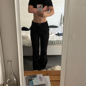 Svarta kostymbyxor med bootcut - Säljer ett par svarta kostymbyxor med bootcut-snitt och hög midja som köptes från bikbok för 400kr. Byxorna har en klassisk look med raka ben som blir vidare nedtill. Använt fåtal gånger. Perfekta för dig som gillar en stilren och tidlös vibe.