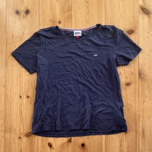 Mörkblå t-shirt Tommy Jeans - Snygg mörkblå t-shirt från Tommy Jeans i mjuk bomull. Klassisk rund hals och korta ärmar, med liten broderad logga på bröstet. Perfekt basic med stilren vibe och diskreta detaljer i kragen. Passar dig som gillar enkel och clean look.