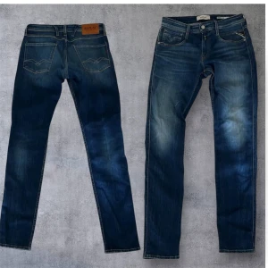 Replay Anbass jeans blå, midwaist - Snygga blå Replay Anbass jeans med klassisk femficksdesign och tydliga slitningar. Jeansen har normal passform, raka ben och midwaist. Materialet är mjukt denim med snygga kontrastsömmar och Replay-logga på fickan.