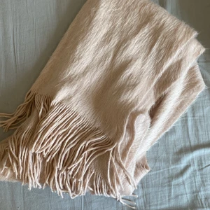 Ljus rosa halsduk  - Supermjuk och fluffig ljus rosa halsduk med långa fransar i kanterna. Perfekt att svepa runt halsen för extra värme och stil. Materialet känns lyxigt. Enkel design som passar till många olika outfits.