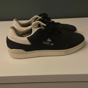 Mörkblå och vita sneakers från Replay - Snygga sneakers från Replay med vita detaljer och logga på sidan. Skorna är knappt använda så de är i bra skick. Skriv gärna om om du har frågor.