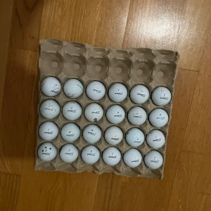 Titliest mix a/b och även några c klass 24 st - Bilderna visar ett flertal golfbollar av märket Titleist, bl.a. truefeel, även några prov1, placerade i en äggkartong. Några av bollarna har markeringar eller linjer ritade på sig. Perfekt för dig som vill ha extra bollar till golfträningen eller spelet. Blandat skick. 24 st