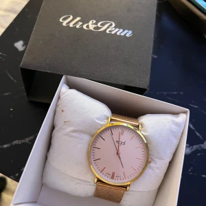 Guldig klocka från Regal Ur&Penn - Stilren klocka från Regal med mesharmband i guld och en ljusrosa urtavla. Klockan har minimalistisk design med tunna index och guldfärgad boett. Perfekt accessoar för dig som gillar en clean look och vill sticka ut med detaljer i guld. ( behövs byta batteri ) har legat bara på min byrå i flera år!