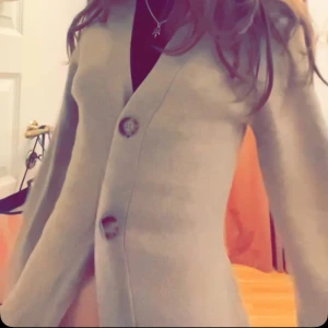 Beige kofta med knappar - Snygg  kofta med två knappar framtill. Koftan har lång ärm och en rak, lite loose passform. Perfekt att slänga över en t-shirt eller topp för en chill och stilren look. Knappt använd 