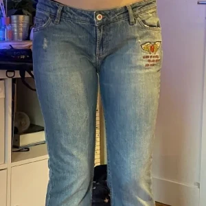 Blå jeans med broderi från Odd Molly - Unika ljusblå jeans med broderad röd ros med vingar och text på fickan från Odd Molly. Bootcut-modell med klassisk femficksdesign och snygg slitning. Jeansen är i bomull och har en cool, avslappnad vibe. Säljer då den inte passade mig :)