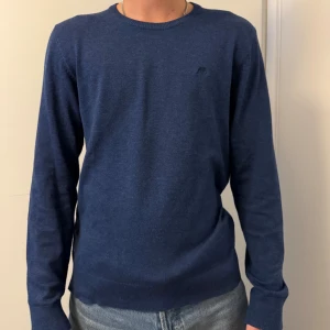 Mörkblå stickad tröja från Lindbergh - Säljer en stilren mörkblå stickad tröja från Lindbergh White i storlek M. Tröjan har rund halsringning, långa ärmar och är tillverkad i mjukt material som passar perfekt till jeans. Enkel och klassisk design utan mönster.