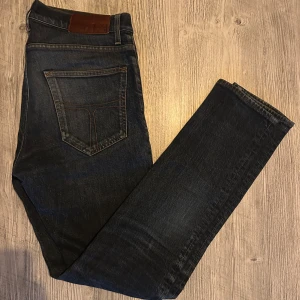 Tiger of sweden mörkblå jeans - Mörkblå T/J jeans med klassisk femficksdesign och snygga kontrastsömmar. Jeansen har en rak passform med något smalare ben och är tillverkade i slitstarkt denim. Perfekta för dig som gillar en tidlös och clean look.