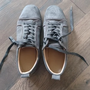 byter gärna mot ett par blå i storlek 42-43 säljes funkar också  - Snygga grå sneakers från Christian Louboutin i mjuk mocka med svarta snören och svarta sulor. Klassisk rund tå och diskret design som passar till det mesta. Skorna levereras med originalpåse och äkthetskort. säljer funkar också 