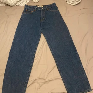 Woodbird Leroy 90s blå jeans 28/30 - Säljer ett par Woodbird Leroy 90s Rinse Jeans i klassisk blå färg. Modellen har raka ben och normal passform, med fem fickor och snygga kontrastsömmar. Perfekt för dig som gillar retrovibbar och enkel stil. Materialet är slitstarkt jeans i bomull.