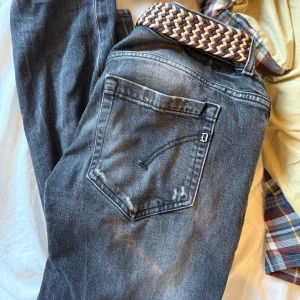 Grå jeans från Dondup George - Snygga grå jeans från Dondup i skinny fit-modell. Jeansen har slitna detaljer och klassiska fickor både fram och bak. Materialet är mjukt denim och de har en mörk tvätt. Perfekta för dig som gillar en smalare passform.