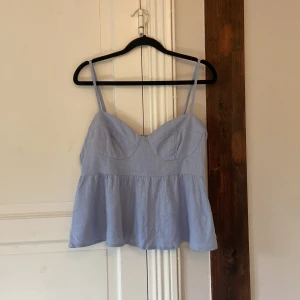 Ljusblå linnetopp från H&M - Supersöt ljusblå linnetopp från H&M med tunna axelband och lätt utsvängd volang nertill. 