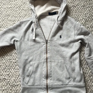 Grå zip hoodie från Polo Ralph Lauren🤩 - Säljer en ljusgrå hoodie från Polo Ralph Lauren i storlek S. Finns några defekter på den så om du undrar så skickar jag såklart( därför den säljs så billigt)🤩✅