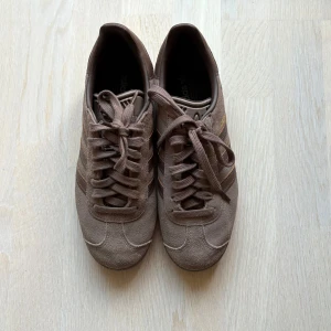 Bruna Adidas Gazelle sneakers mocka 38 2/3 - Bruna adidas gazelle i mocka. Knappt använda och är väl omhändertagna. Strl 38 2/3. Ingen kartong!
