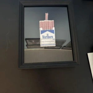 Rum dekor - Säljer en snygg och lite annorlunda dekoration som föreställer ett Marlboro-paket fyllt med fejkade sedlar. Tavlan är inramad i en svart ram och går att antingen hänga på väggen eller ställa på ett skrivbord/hylla.  Perfekt för dig som vill ha något unikt och samtalsväckande i rummet. Sedlarna är självklart fejk.  Anledningen till försäljningen är att den inte längre passar in i mitt rum. Tavlan är i mycket fint skick och har inga skador. PRIS GÅR ATT DISKUTERA VID SNABB AFFÄR